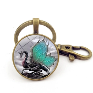 Detailed view of bronze dragon keychain with green winged illustration and glass cabochon