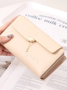 Elegant beige long wallet with heart pendant and trifold flap design on magazine background