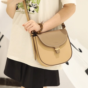Detail van de crossbodytas met gouden bladsluiting en contrasterende stiksels op PU-leer