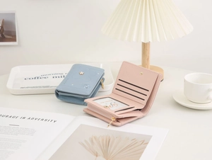 Detail view of pink and blue bifold wallets showing card slots and floral embroidery