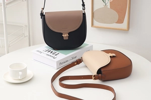 Detail van de crossbody tas met gouden bladsluiting en gestructureerd imitatieleer