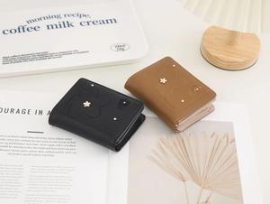Detail of compact PU leather tri-fold wallets with floral embroidery and gold accents