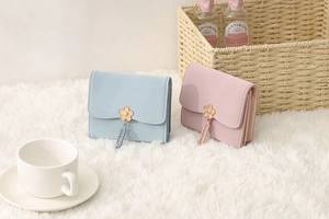 Detail of short wallets with floral metal clasps in pastel blue and pink faux leather
