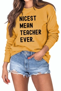 Detail of Nicest Mean Teacher Ever text on ginger yellow crewneck sweatshirt