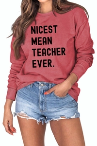 Detail of Nicest Mean Teacher Ever slogan on brick red long sleeve crewneck sweatshirt