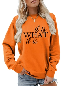 Detail eines orangefarbenen Sweatshirts mit schwarzem 'it is WHAT it is' Grafikaufdruck