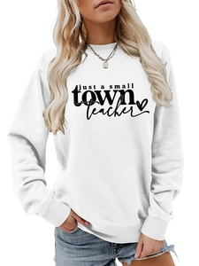 Gros plan sur l'imprimé 'just a small TOWN Teacher' noir sur un sweatshirt blanc en coton