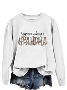 Close-up of white crewneck sweatshirt featuring floral GRANDMA text and denim shorts