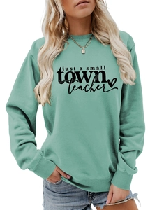Détail d'un sweat sarcelle avec le texte just a small town teacher et un motif de cœur