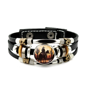 Detalle de pulsera de cuero multicapa con silueta de vaquero al atardecer en el dije