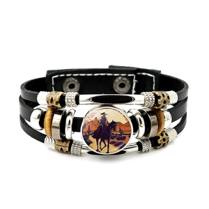 Detalle de pulsera de cuero multicapa con silueta de vaquero y cuentas de bronce