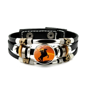 Detalle de pulsera de cuero multicapa con dije de silueta de vaquero al atardecer