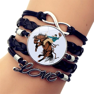 Dettaglio di un bracciale multistrato in pelle con simbolo dell'infinito e fascino cowboy