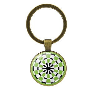 Detail of dartboard keychain with green and black target pattern under glass dome