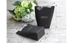 Matte black paper gift bag with grey silk bow and gold Merci Beaucoup foil print