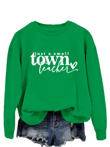 Détail de l'imprimé blanc 'just a small town teacher' sur un sweat vert à col rond