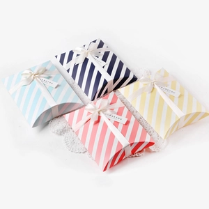 Detail of colorful striped pillow boxes with white ribbons and thank you gift tags
