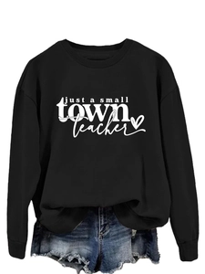 Gros plan de l'imprimé 'just a small town teacher' sur un sweat à col rond noir