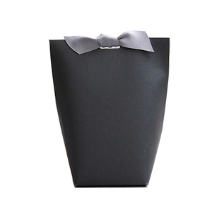 Minimalist black matte trapezoid gift bag with a grey ribbon bow on a white background