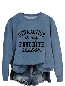 Close-up of fabric texture and 'GYMNASTICS is my FAVORITE season' print on blue sweatshirt