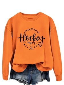 Detail of orange long sleeve sweatshirt featuring black Hockey Mom Life print design