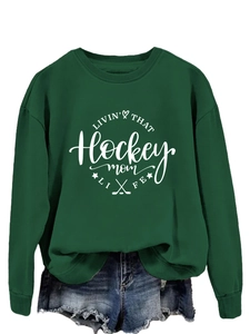 Close-up of forest green hockey mom sweatshirt featuring white graphic lettering and star icons