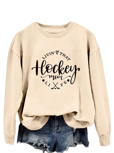 Detail of beige 'Hockey Mom' sweatshirt with black typography and raw hem denim shorts