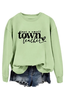 Détail du col rond et de l'imprimé noir sur le sweat-shirt vert clair en coton