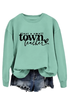 Détail du sweat vert menthe avec inscription noire just a small town teacher et un coeur