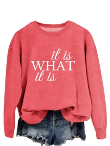 Detail eines korallenroten Sweatshirts mit weißem 'it is WHAT it is' Textdruck