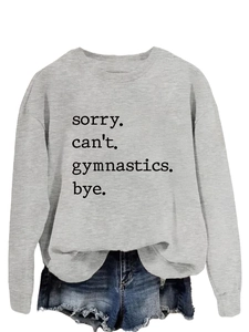 Detail of grey sweatshirt with 'sorry can't gymnastics bye' print and denim shorts
