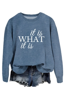 Detail des weißen 'it is WHAT it is' Schriftzugs auf einem blauen strukturierten Sweatshirt