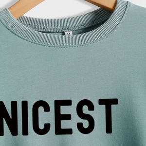 Green long sleeve sweatshirt with Nicest print and ribbed crew neck on a hanger