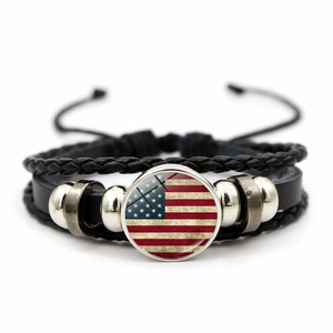 Macro view of multi-layer leather bracelet featuring vintage flag charm and braided cords