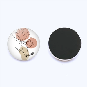 Macro view of round glass fridge magnet showing artistic floral lines and magnetic back