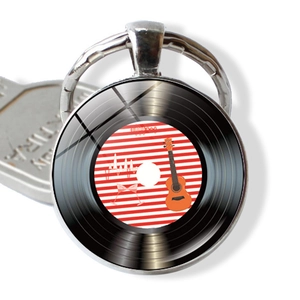 Dettaglio macro del portachiavi a disco in vinile con design ukulele e cabochon in vetro