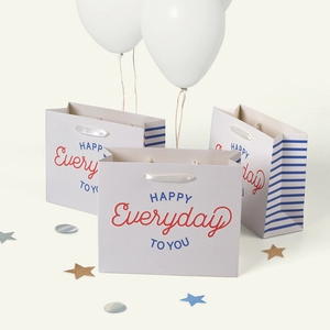 Gray paper gift bag with navy stripes and HAPPY TO YOU print for festive celebrations