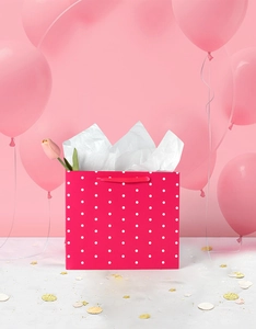 Detail of hot pink polka dot gift bag with white tissue paper and pink tulip decor