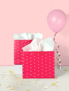 Detailed view of pink polka dot paper gift bags with ribbon handles and tissue paper