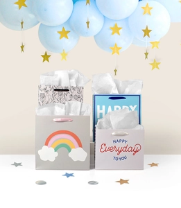 Detail view of four colorful cartoon gift bags with silk handles and decorative tissue paper