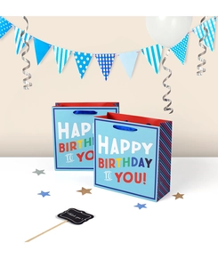 Detailed view of blue Happy Birthday gift bags with ribbon handles in party setting