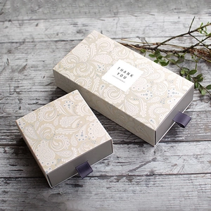 Chinese vintage paisley patterned drawer gift boxes with purple ribbon handles on wood table