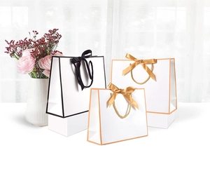 Detail of luxury white gift bags with bow knots and contrast borders for jewelry