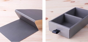 Detail of dark grey drawer box showing internal structure and black ribbon pull handle