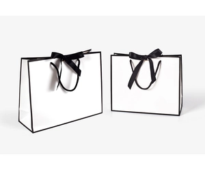 Close-up of minimalist white gift bags with black borders and elegant ribbon bows