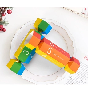Colorful candy-shaped gift box with geometric patterns on a white plate with berries