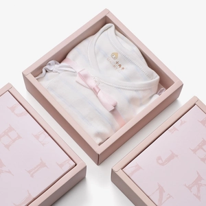 Detail of newborn striped baby onesie with pink bow in elegant gift packaging