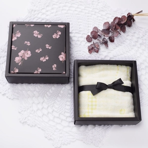 Elegant black gift box with pink cherry blossoms and a yellow checkered cotton towel