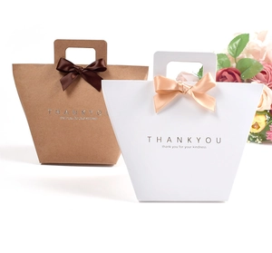 Detail von Kraftpapier-Geschenktüten mit Goldfolienprägung und eleganten Satin-Schleifen