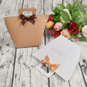Minimalist kraft paper gift bags with handles and ribbon bows for premium wedding favors